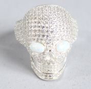 A SILVER OPAL EYE SKULL RING.
