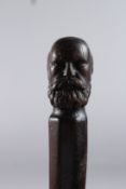 A HARDWOOD WALKING CANE, the handle carved with a bearded MAN. 30ins long.