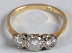 AN 18CT GOLD AND DIAMOND THREE STONE RING.