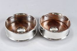 A PAIR OF PLAIN CIRCULAR PLATED WINE COASTERS with wooden bases.