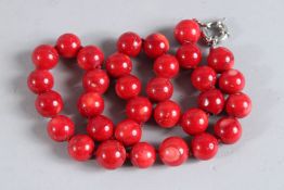 A STRING OF THIRTY-TWO LARGE CORAL BEADS.