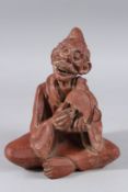 A TERRACOTTA SEATED FIGURE playing a cymbal. 9ins high.