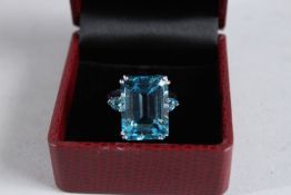 A LARGE SILVER EMERALD CUT BLUE TOPAZ RING.