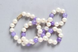 A STRING OF LAVENDER JADE BEADS AND PEARLS with a gold clasp. 20ins long.