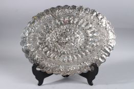 A LARGE EGYPTIAN SILVER OVAL MIRROR with repousse and scroll decoration. 12ins x 16ins.