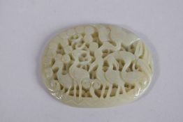 A CHINESE CARVED AND PIERCED JADE OVAL PLAQUE, depicting cranes and foliage, 7cms x 5.5cms.