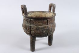 AN ARCHAIC BRONZE CENSER with looped handles, on three legs. 8ins diameter.