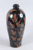 A CHINESE POTTERY VASE, dark brown glaze painted with leaves. 30cms high.