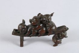 A JAPANESE BRONZE OKIMONO OF THREE PIGS on a bench. 4.5ins long.