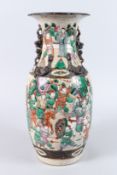 A LATE 19TH CENTURY SATSUMA TWIN HANDLED VASE, painted all over with warriors (rim repaired).