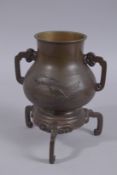 A JAPANESE BRONZE TWIN HANDLE VASE WITH RELIEF CARP DECORATION, raised on tripod legs, the base with