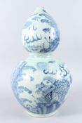 A LARGE CHINESE BLUE AND WHITE PORCELAIN GOURD SHAPE VASE, painted with dragons. 54cms high.