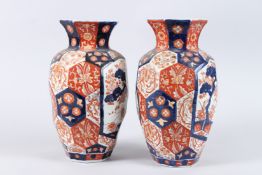 A PAIR OF JAPANESE IMARI PORCELAIN VASES of hexagonal form, painted with panels of trees in a