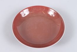 A CHINESE PORCELAIN DISH, with copper red glaze, square seal mark to base. 19.5cms diameter.