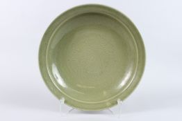 A LARGE CHINESE PORCELAIN CELADON GLAZED DISH, with incised decoration. 41.5cms diameter.