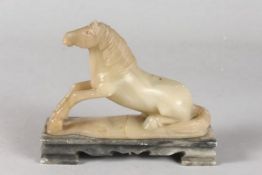 A CHINESE QING DYNASTY JADE OR GREEN SOAPSTONE CARVING OF A RECUMBENT HORSE, mounted to a