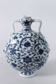 A CHINESE PORCELAIN BLUE AND WHITE MOON FLASK, painted with a stylised floral design. 28cms high.