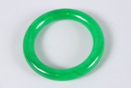 A CHINESE APPLE GREEN JADE BANGLE. 3.25ins diameter.