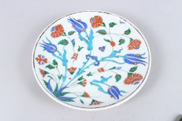 A TURKISH OTTOMAN IZNIK CIRCULAR PORCELAIN PLATE with red and blue flowers. 9.5ins diameter.