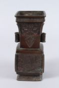 AN 18TH / 19TH CENTURY CHINESE BRONZE ARCHAIC FORM TWIN HANDLED VASE, with stylised scrolling