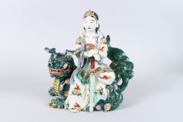 A 19TH CENTURY JAPANESE POTTERY FIGURE GROUP, modelled as a female figure with sword seated on a
