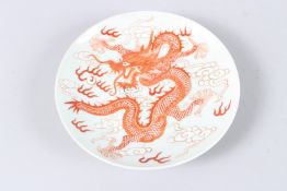 A CHINESE PORCELAIN CIRCULAR DISH, painted in iron red depicting a dragon, six character mark to