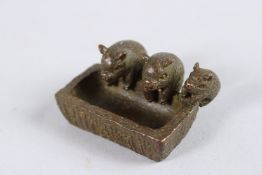 A JAPANESE BRONZE OF THREE SMALL PIGS at a trough. 1.5ins long.
