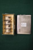 A set of four silver napkin rings and a silver cigarette case.
