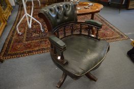 A green leather button upholstered office swivel armchair.
