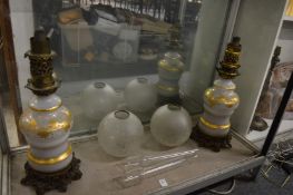 A pair of decorative opaque and glass and gilded oil lamps with etched glass shades (one shade