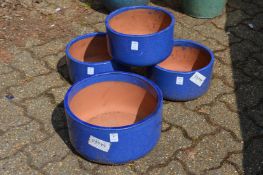Circular blue glazed terracotta plant pot and a set of three matching plant pots.