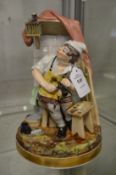 Continental porcelain figure of a cobbler at work with a bird in a cage above his head.