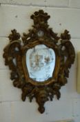 An early gilt framed shield shaped mirror, possibly Italian, with carved decoration.