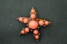 A Kenneth Lane faux tortoiseshell and coral starfish shaped brooch.