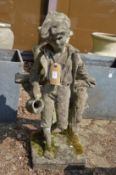 A reconstituted stone garden fountain modelled as a boy against a fence holding a jug.