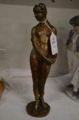 A cast bronze model of a standing female nude.
