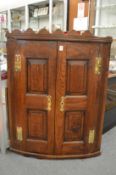 A George III oak hanging corner cupboard with a pair of panelled doors.