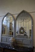 A pair of arch shaped garden mirrors with ornate wrought iron decoration.