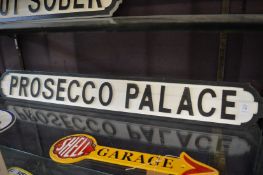 A novelty carved wood and painted sign 'Prosecco Palace'.