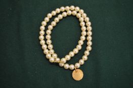 Pearl necklace with coin pendant.