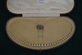 A good pearl necklace with amethyst and yellow metal clasp.