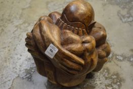 An unusual carved wood figure of a crouching man.