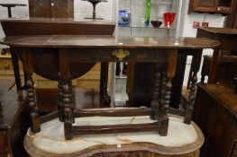 An oak single drawer side table with a drop flap to each end on turned gate-leg supports.