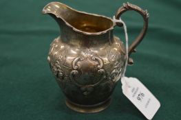 An embossed silver cream jug.