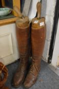 A pair of brown leather military boots with original wooden trees.
