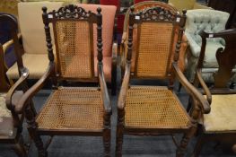 A pair of oak framed armchairs with cane work seats and back panels.