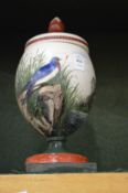 A pottery vase and cover painted with birds in a naturalistic setting.