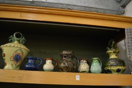 A collection of puzzle jugs and two large colourful pottery wine ewers or storage jars.