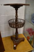 A mahogany circular stand with revolving galleried under tier on a platform base.