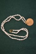 A pearl necklace with coin pendant.